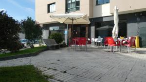 un patio con mesas, sillas y una sombrilla en Albergue cafetería Río Sar, en Padrón