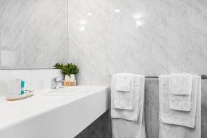 ein Badezimmer mit einem Waschbecken, einem Spiegel und Handtüchern in der Unterkunft Bayscape Studio Glenelg in Glenelg