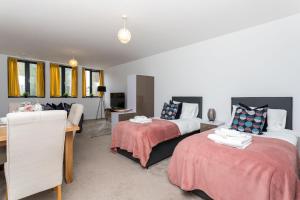 a bedroom with two beds and a desk and a living room at Studio Flat in the Heart of Crawley- Apartment 7 in Crawley