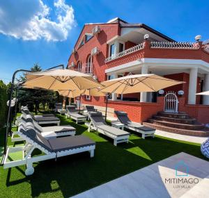 a group of chairs and umbrellas in front of a building at Lux Villa Mitimago in Niš