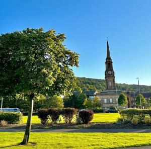 eine Kirche mit einem Uhrturm in einem Park in der Unterkunft THE LAZY LION - Spacious 2 Bedroom - Town Centre Holiday Home Apartment in Port Glasgow