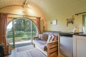 uma sala de estar numa pequena casa com um sofá em Pendragon Pod em Axminster