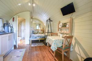 a room with a table and a bed in a tiny house at Pendragon Pod in Axminster +7 photos