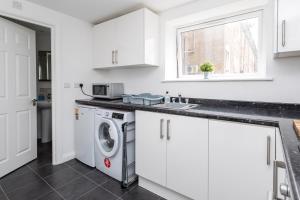 a kitchen with a washing machine and a window at Flat 7- Spacious Studio Flat in The Heart of Crawley in Crawley