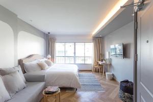 a white bedroom with a bed and a couch at Q HOME_iconsiam in Khlong San