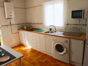 een keuken met een wastafel en een wasmachine bij Chalet Mari Carmen in Chiclana de la Frontera