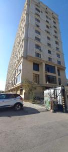 a car parked in front of a tall building at Kozhomkul Apartment in Bishkek in Bishkek