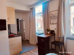 a room with a desk and a kitchen with a window at SalzinnesChezSoi 2 in Namur