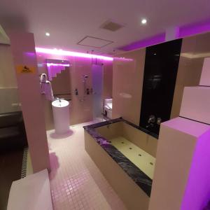 baño con bañera, aseo y luces púrpuras en King Motel王者 en Taoyuan