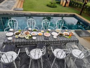 - une table avec des assiettes de nourriture à côté d'une piscine dans l'établissement SEA VILLA HỒ TRÀM, à Ho Tram
