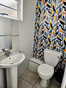 y baño con aseo, lavamanos y cortina de ducha. en Sea Breeze Manor - Gold Unit, en East London