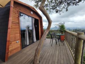 a wooden deck with a table and a tree at Breeze Glamping -Guatape in El Peñol