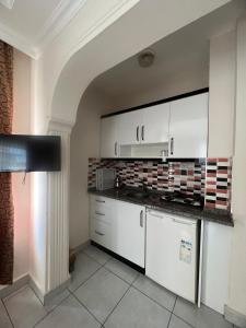 a kitchen with white cabinets and a tile wall at Safran Apart Hotel in Alanya