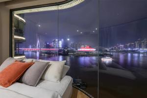 a couch in a room with a view of a city at Baihong.Riverview Apartment in Chongqing