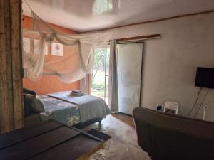 a bedroom with a bed and a window and a couch at Vulture's View 3 in Hartbeespoort