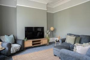 uma sala de estar com 2 sofás e uma televisão de ecrã plano em Montpellier Villa 