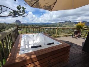 a hot tub on a deck with an umbrella at Breeze Glamping -Guatape in El Peñol