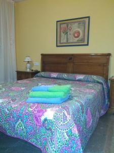 a bed with green and blue pillows on it at Casa Rosa in Alcañiz