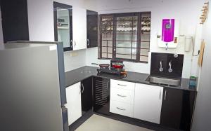 特里凡得琅的住宿－AASTHA，厨房配有白色橱柜和黑色台面