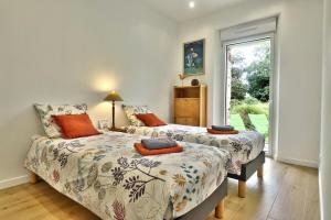 two beds in a room with a window at La longère de Poulrinou in Bohars