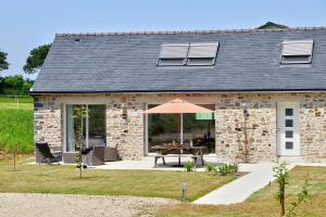 een stenen huis met een tafel en een paraplu bij La longère de Poulrinou in Bohars