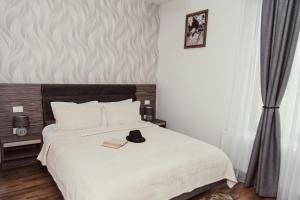 a bedroom with a white bed with a black headboard at Poiana Verde Garden House in Poiana Campina