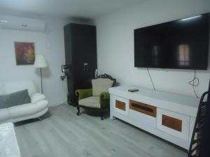 a living room with a couch and a tv on the wall at arad rooms & apartments חדרי אירוח ערד in Arad