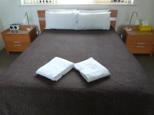 a bedroom with a bed with two white towels on it at Glenelg Holiday Apartments - Corfu in Adelaide