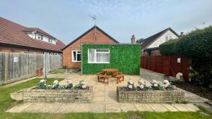 a backyard with a green building with a picnic table at Stunning 3 Bedroom 2 Bathroom Bungalow by CozyNest in Earley