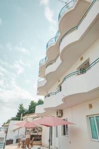 un bâtiment avec des tables et des parasols devant lui dans l'établissement Beachfront Apartment, à Himarë
