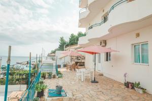 un patio con mesas y sombrillas frente a un edificio en Beachfront Apartment, en Himare