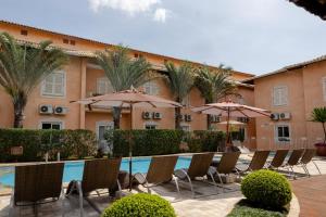 a pool with chairs and umbrellas in front of a hotel at Hotel Cordialle in São Roque