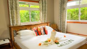 Un dormitorio con una cama blanca con flores. en Bwaver Cottage, en La Digue