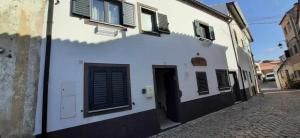 a white building with a door and windows on a street at Casa das Matriarcas - Casa da Avó Benvinda in Belmonte