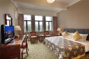 a hotel room with a bed and a desk with a television at Jing An Hotel in Shanghai