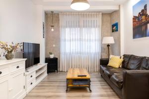 sala de estar con sofá de cuero y TV en Amplio, luminoso y moderno cerca del Casco Viejo en Bilbao
