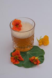 a glass of liquid with flowers on a green leaf at JETTY Montreux in Montreux