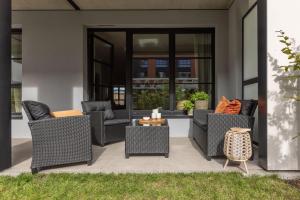 a patio with wicker chairs and a table at Solidarność Three Bedroom & Garden Apartment in Gdańsk