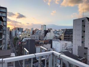 a view of a city at sunset from a balcony at Mezon Akihabara Guest House in Tokyo