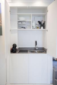 a kitchen with white cabinets and a sink at U Scrusciu d’u Mari Luxury Suite in Cefalù