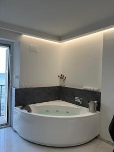 uma grande banheira branca numa casa de banho com uma janela em U Scrusciu d’u Mari Luxury Suite em Cefalù