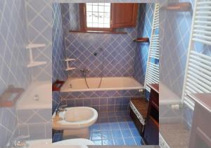 a blue tiled bathroom with a toilet and a sink at Condominio Pisella in Pieve di Panzano