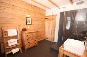 ein Badezimmer mit Holzwänden, einem Waschbecken und einer Dusche in der Unterkunft La Chaumiere - Luxury Traditional Chalet, Châtel in Châtel