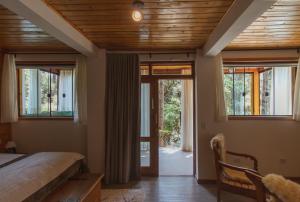 een slaapkamer met een bed en glazen schuifdeuren bij Pousada Canto da Nascente in Monte Verde