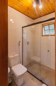 uma casa de banho com um WC e uma cabina de duche em vidro. em Pousada Canto da Nascente em Monte Verde