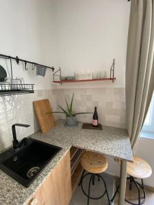 a kitchen with a counter with a sink and two stools at Charming apartment in the heart of Gellért area. in Budapest