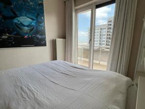 um quarto com uma cama e uma grande janela em Sfeervol Appartement met Zeezicht em Middelkerke