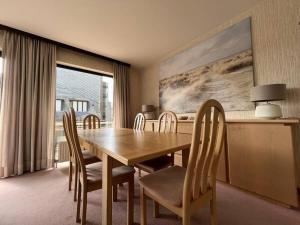 uma sala de jantar com uma mesa de madeira e cadeiras em Sfeervol Appartement met Zeezicht em Middelkerke