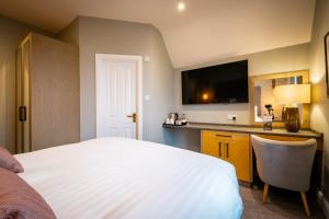 a bedroom with a bed and a desk with a television at Ambleside Fell Rooms in Ambleside