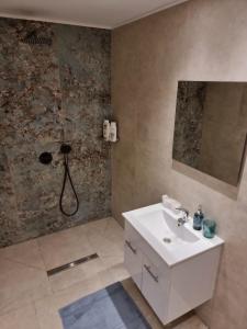 uma casa de banho com um lavatório branco e um chuveiro em ביקתה בים em Tel Aviv